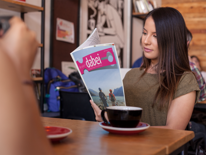 Junge Frau liest das Magazin 21/22 in einem Cafe